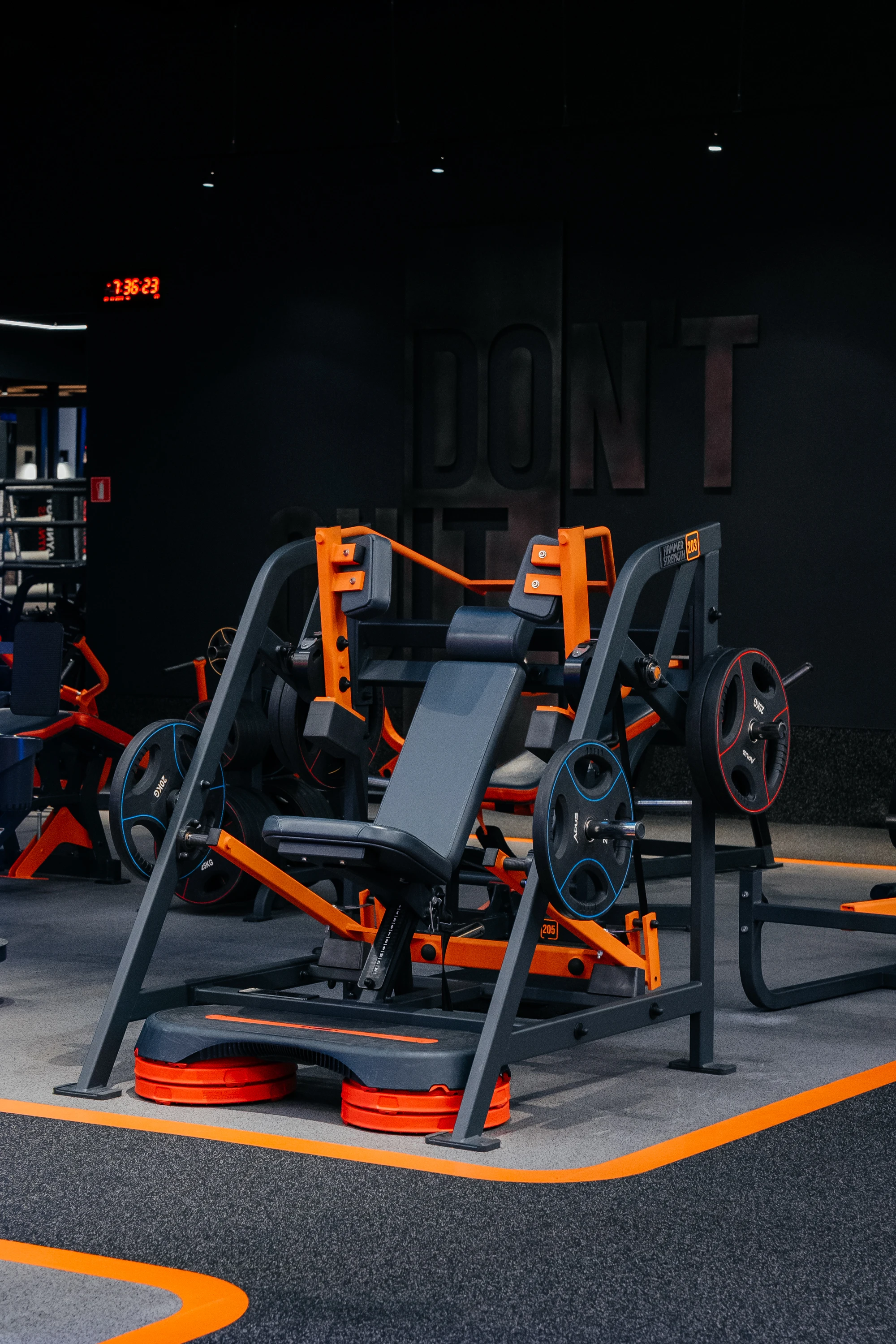 Композиція з силовим тренажером з яскравим кольоровим контрастом та мотивуючим написом на стіні