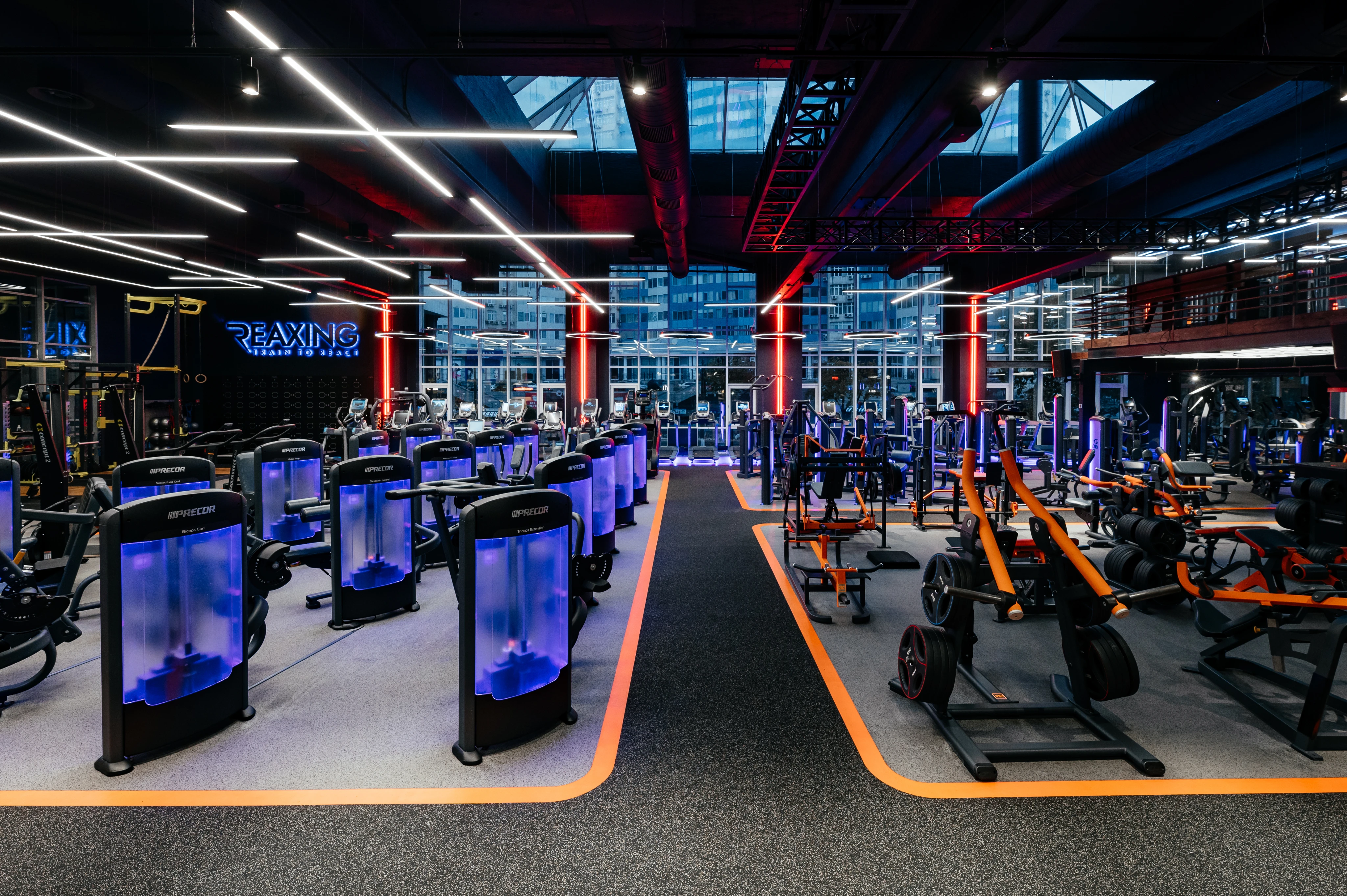 Бігові доріжки з неоновим освітленням, сучасне обладнання та великі вікна в приміщенні